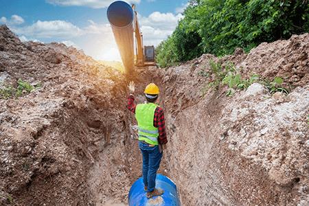 Worker Installing Pipe Underground