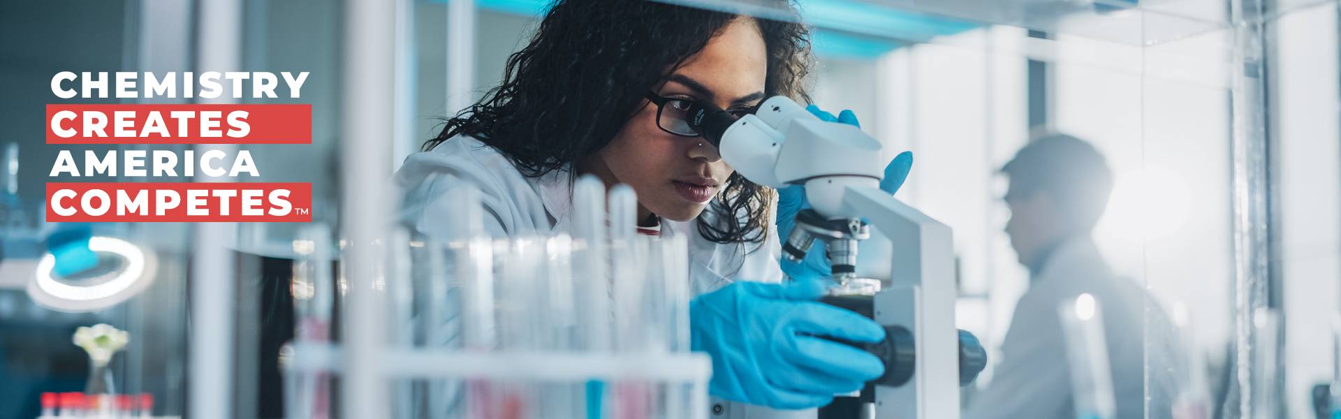 Chemistry Creates America Competes Chemist in Lab Looking Through Microscope