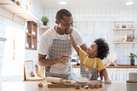 Cheerful African American father and son baking.